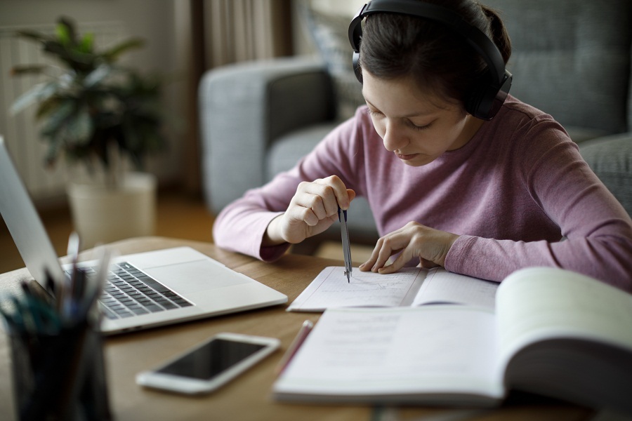 Teenage girl with headphones studying at home